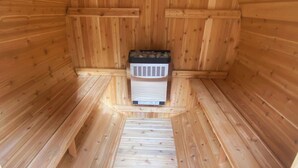 Una sauna con interior de madera, un banco y un calentador.