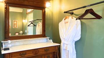 A bathroom with a wooden vanity, a large mirror, and a robe hanging on a rack.
