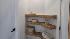 Une petite salle de bain avec des étagères en bois, un sol carrelé à motifs hexagonaux et une porte.
