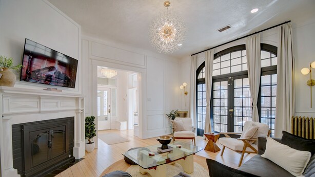 Un salon moderne avec une cheminée, un téléviseur, une table basse en verre et un canapé.