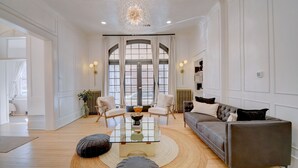 Un salon spacieux avec un grand canapé, deux fauteuils, une table basse en verre et un tapis rond.