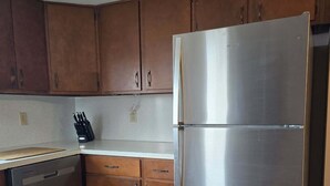 A kitchen with wooden cabinets, a stainless steel refrigerator, and a dishwasher. - Family-friendly farmhouse property, rural setting, 10 minutes from Tiffin, OH. (Republic)