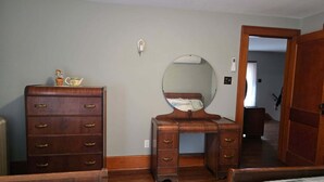 A bedroom with two wooden dressers, a round mirror, and a bed with a quilted cover. - Family-friendly farmhouse property, rural setting, 10 minutes from Tiffin, OH. (Republic)
