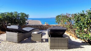 A terrace with wicker furniture overlooking a beach and the sea. - Quiet 79m2 apartment by the sea with garden and communal pool (Povljana)