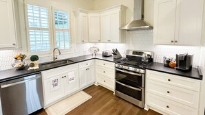 A modern kitchen with white cabinetry, a stainless steel stove, and a dishwasher.