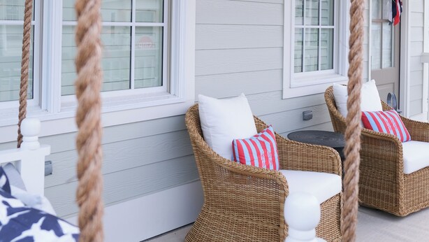 A porch with wicker furniture, white railings, and a ceiling fan.