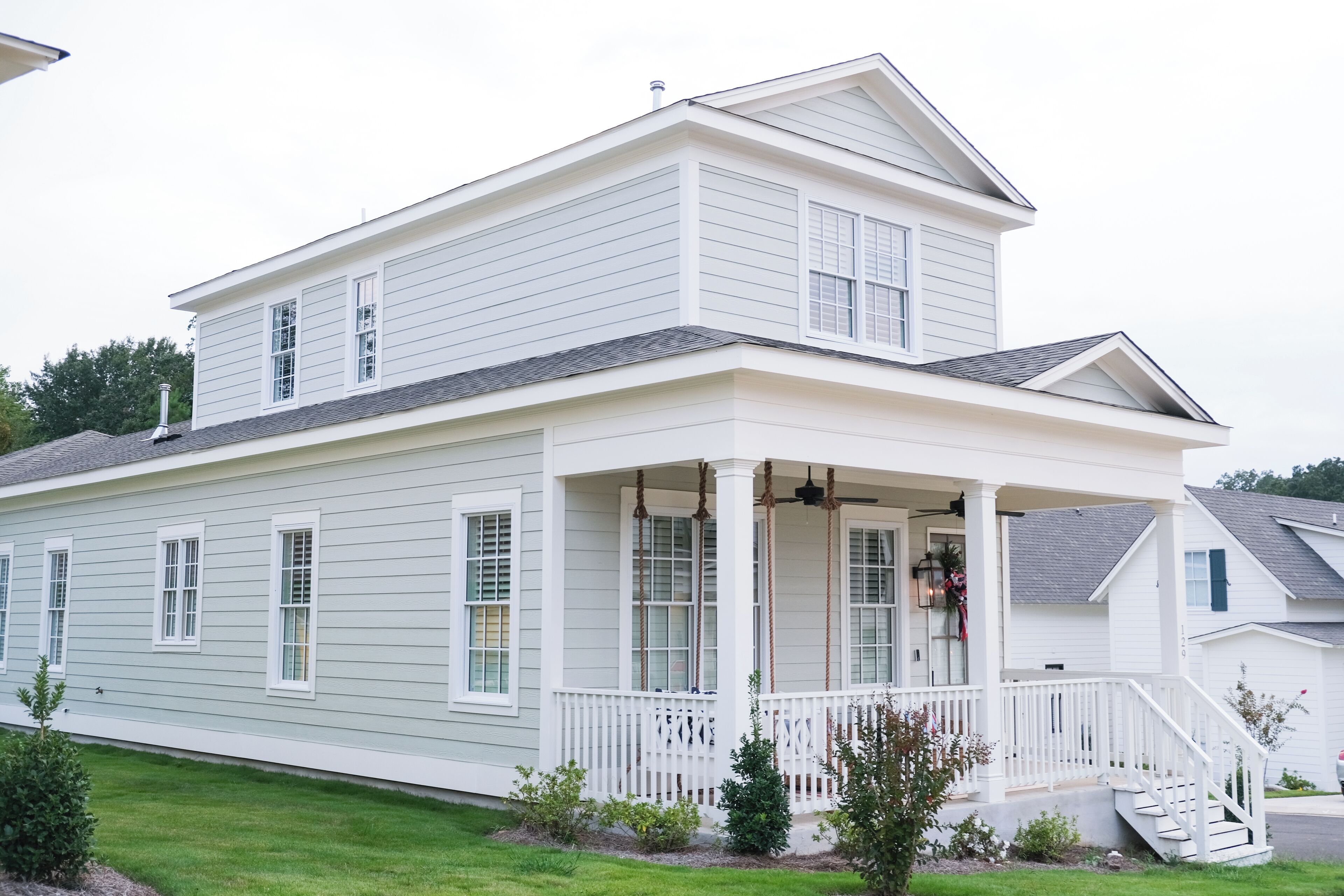 A two-story house with a porch, a staircase, and a small garden.
