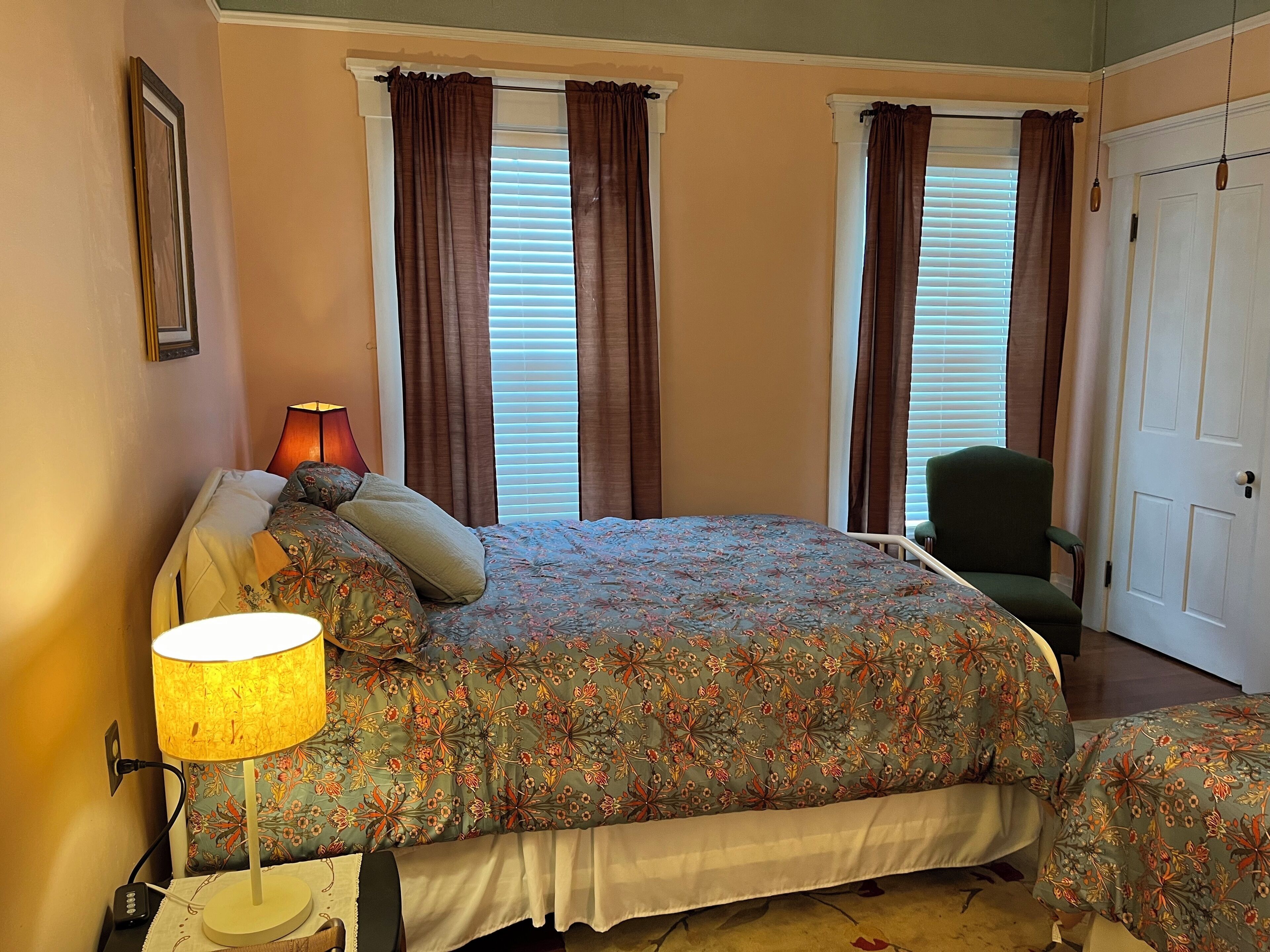 A bedroom with a bed, a chair, a lamp, and a door.