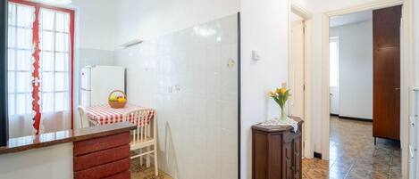 A kitchen with a red and white checkered tablecloth, a wooden cabinet, and a tiled floor.