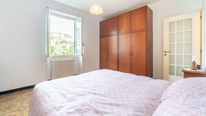 Un dormitorio con cama, armario, ventana y puerta.