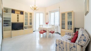 Un salón amplio con comedor, una araña y un sofá tapizado con motivos florales.