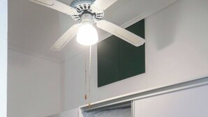 A laundry room with two front-loading washing machines, a ceiling fan, and a built-in shelving unit for storing linens.