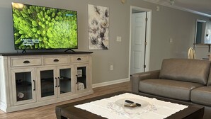 A living room with a television, a cabinet, a coffee table, and a sofa. - Charming First Floor 3-bedroom condo with AC, WiFi in tranquil Pawleys Island (Pawleys Island)