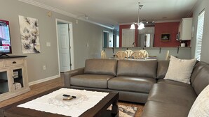 A living room with a brown leather sofa, a wooden coffee table, and a TV on a stand. - Charming First Floor 3-bedroom condo with AC, WiFi in tranquil Pawleys Island (Pawleys Island)