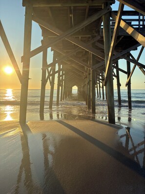 A wooden pier structure extending into the water with a clear view of the ocean and a sunset in the background. - Charming First Floor 3-bedroom condo with AC, WiFi in tranquil Pawleys Island (Pawleys Island)