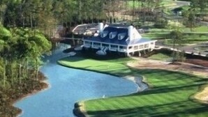 A house with a large deck overlooking a lake, surrounded by lush greenery. - Charming First Floor 3-bedroom condo with AC, WiFi in tranquil Pawleys Island (Pawleys Island)