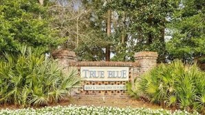 A sign with "TRUE BLUE" and "GOLF & DINING OPEN TO PUBLIC" indicating a public golf and dining facility. - Charming First Floor 3-bedroom condo with AC, WiFi in tranquil Pawleys Island (Pawleys Island)