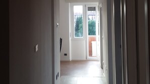 A hallway leading to a balcony with a view of greenery and buildings. - Vroom508 (Verona)
