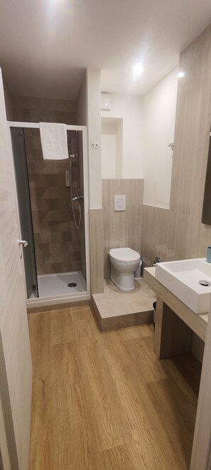 A modern bathroom with a glass-enclosed shower, a toilet, and a sink. - Vroom508 (Verona)
