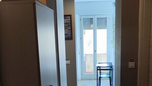 A hallway with a wooden ceiling, a door with a handle, a gas cylinder, and a table with chairs in the background. - Vroom508 (Verona)