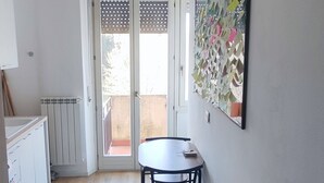 A narrow hallway with a wooden floor, a dining table with chairs, a radiator, and a sliding glass door leading to an outdoor area. - Vroom508 (Verona)