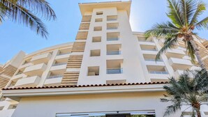Een hotel met meerdere verdiepingen, met een modern design, voorzien van balkons en een centrale ingang.