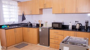 Eine Küche mit Holzschränken, einem Kühlschrank, einer Mikrowelle, einem Wasserkocher und einem Toaster.
