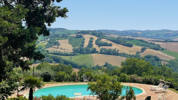 Ein Pool, umgeben von üppiger Vegetation und einer malerischen Aussicht auf sanfte Hügel.