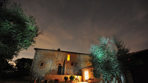 Un bâtiment en pierre avec une entrée illuminée et un petit patio.