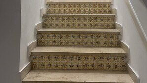 Un escalier recouvert de carreaux décorés mène à une porte blanche.
