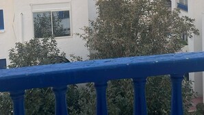 Une vue sur des bâtiments blancs rehaussés d’éléments bleus, des antennes paraboliques et une balustrade de balcon.