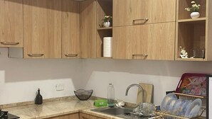 Une cuisine avec des meubles de rangement en bois, un lave-linge et un plan de travail sur lequel se trouvent divers objets.