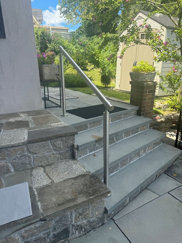 A set of stone steps with a metal handrail leading to a door.