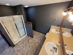 A bathroom with two sinks, a glass shower enclosure, and a mirror with lights. - Charming 4-bedroom house with AC, WiFi. 10 mins to WSU (Kechi)