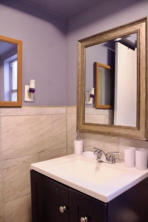 Une salle de bain avec un lavabo blanc, des meubles sombres et un grand miroir avec un cadre en bois.