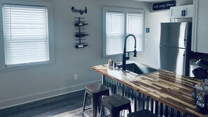 A modern kitchen with a wooden countertop, stainless steel appliances, and a wine rack on the wall.