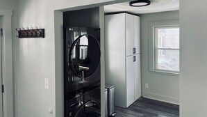 A modern kitchen with a black refrigerator, a white cabinet, and a wooden ceiling ornament.
