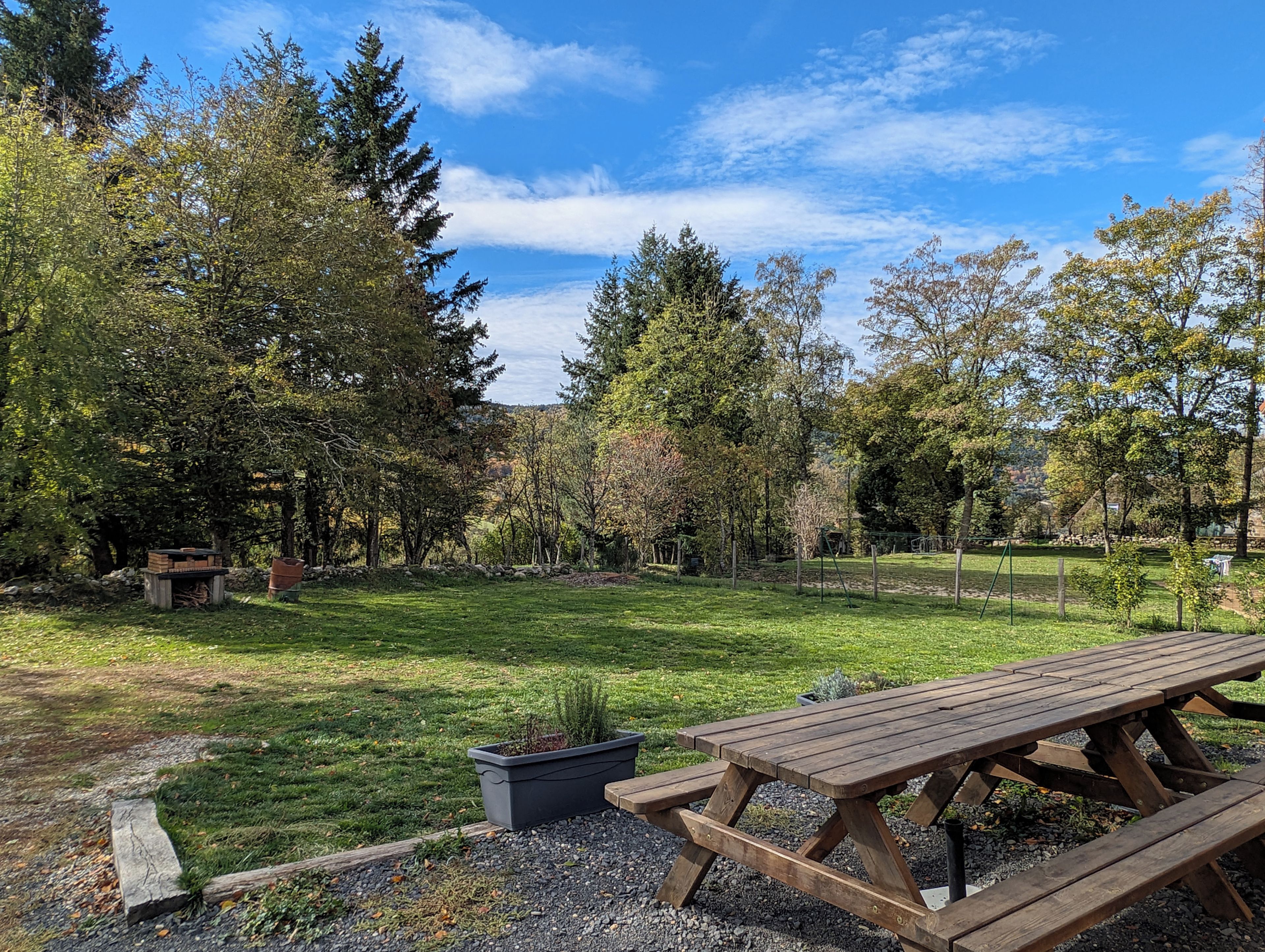 A picnic table in a park with trees and a stone wall in the background.