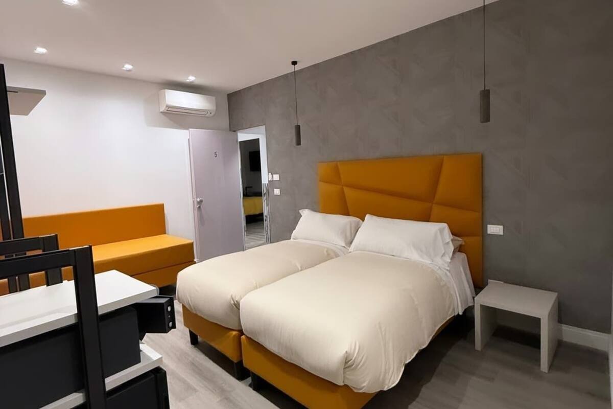 A modern hotel room with a double bed, a small desk, and a chair.