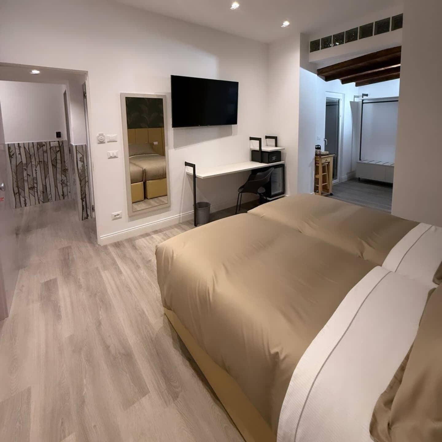 Un dormitorio moderno con una cama grande, un escritorio y un televisor.