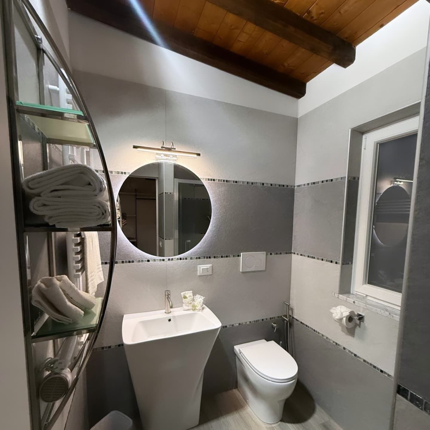 A bathroom with a white sink, a toilet, a mirror, and a towel rack.