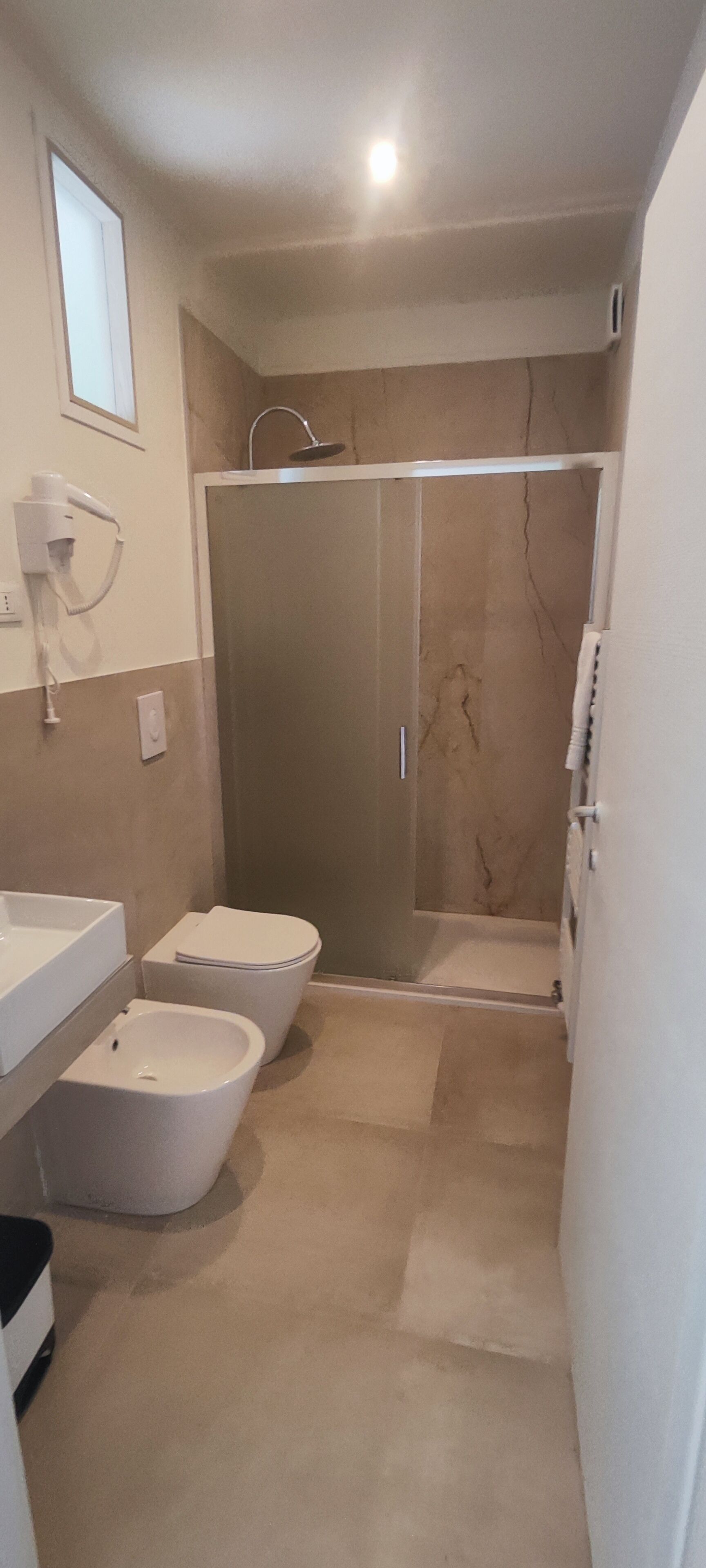 A bathroom with a shower, two toilets, and a sink.