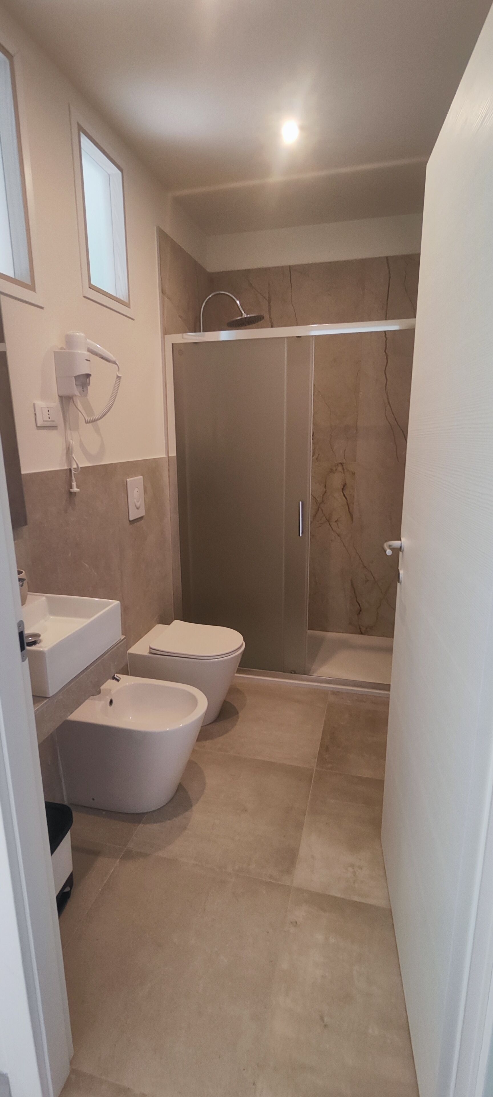 A bathroom with a bidet, toilet, and shower.