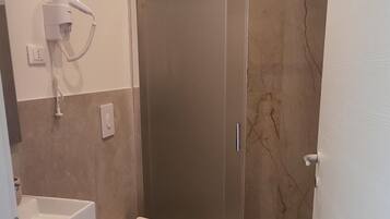 A bathroom with a bidet, toilet, and shower.