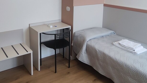 A small, neatly arranged room with a desk, chair, and a bed. - Vroom509 (Verona)