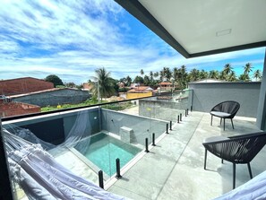 Uma área de piscina no terraço com vista desobstruída do bairro circundante, incluindo palmeiras e edifícios.