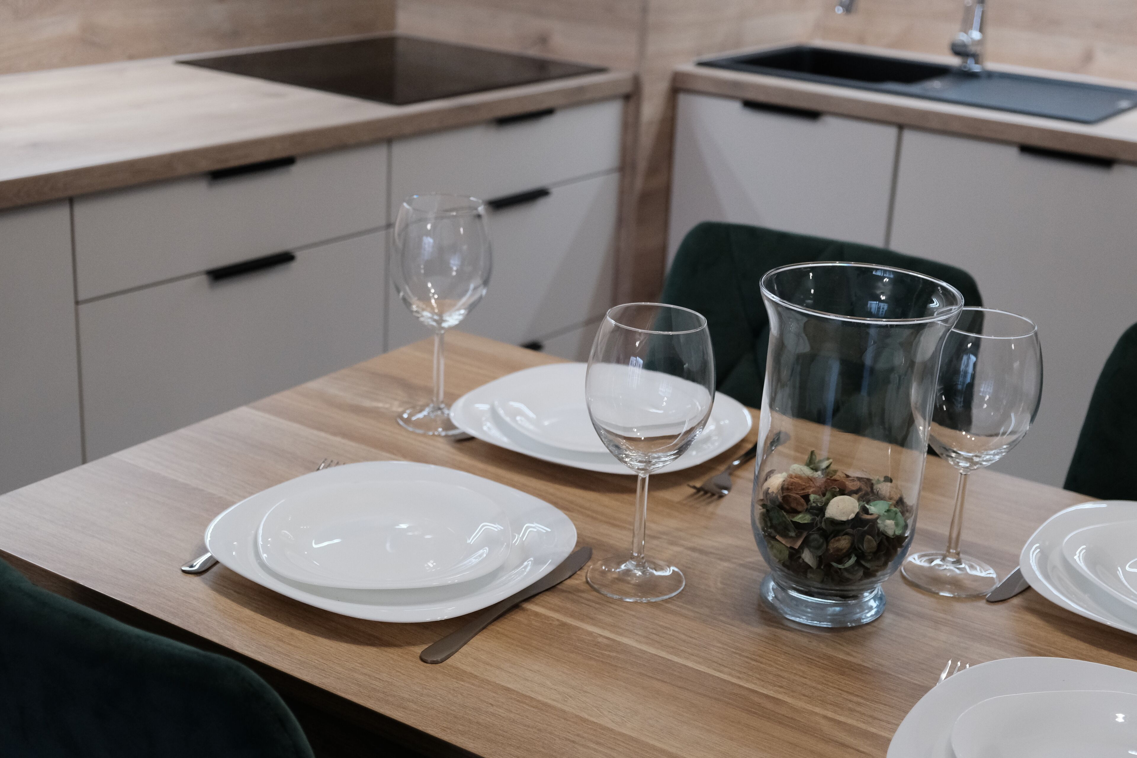 Een eettafel gedekt met borden, bestek en wijnglazen, met een decoratieve schaal in het midden.