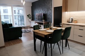 Een moderne eethoek met een houten tafel, groene stoelen en een aan de muur bevestigde televisie.
