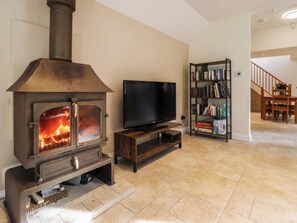 A living room with a wood-burning stove, a television on a stand, and a bookshelf filled with books. - 1 bedroom accommodation in Frithville, near Lincolnshire (Frithville, near Lincolnshire)