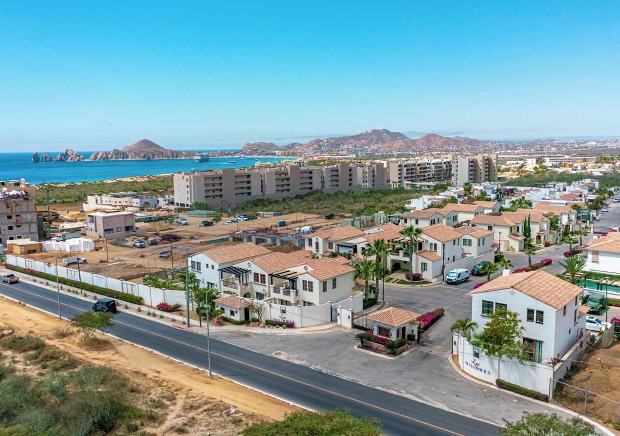 Zona residencial con edificios de varios pisos, una carretera y vista al mar.